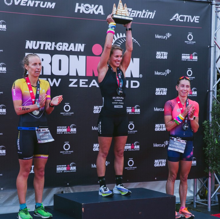 Subaru brand ambassador Hannah Wells (centre) celebrates winning the 2021 Nutri-Grain IRONMAN New Zealand on debut yesterday. PHOTO CREDIT: JEMMA WELLS.