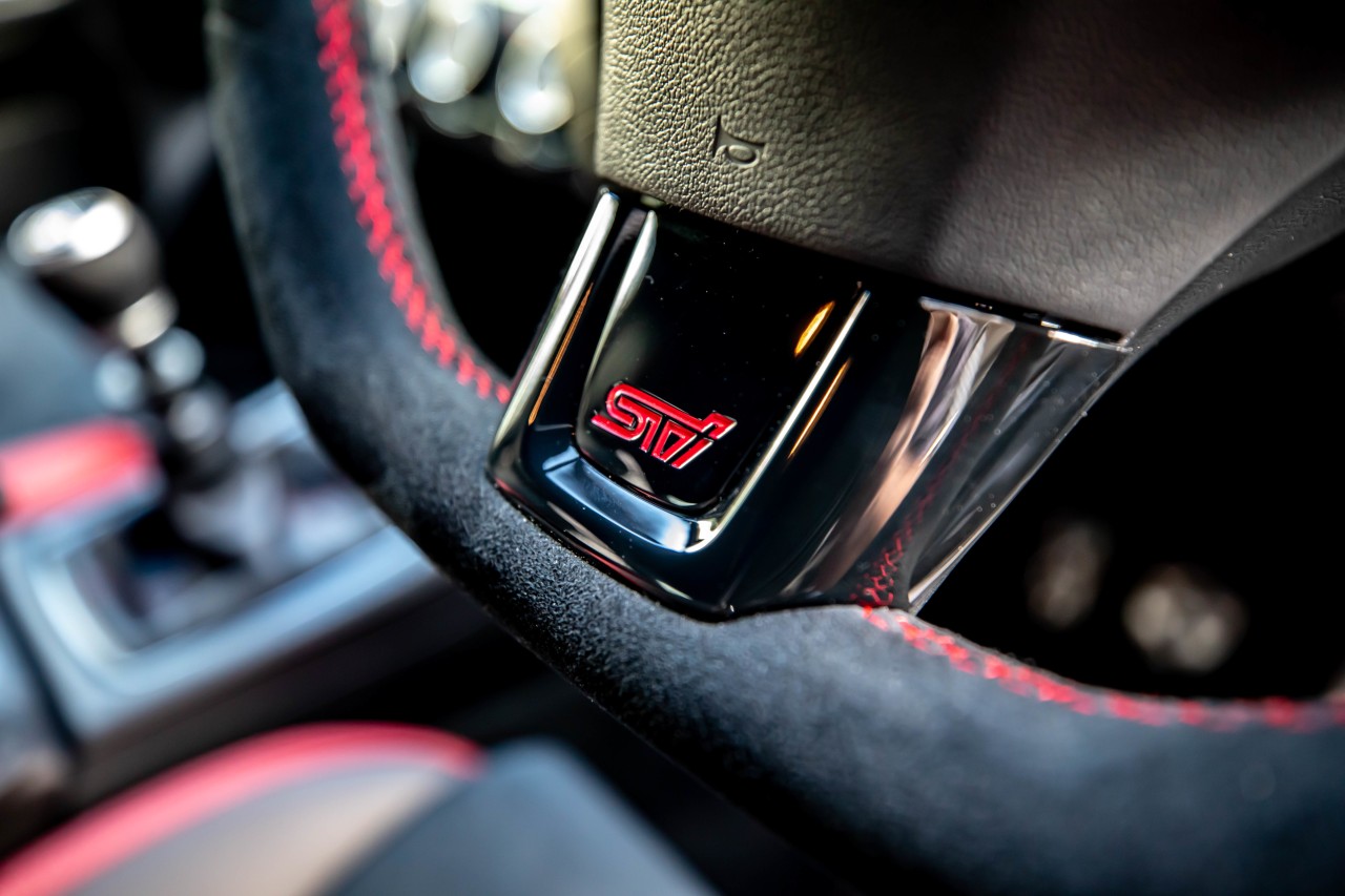 The SAIGO WRX features a suede D-shaped steering wheel with a STI logo.