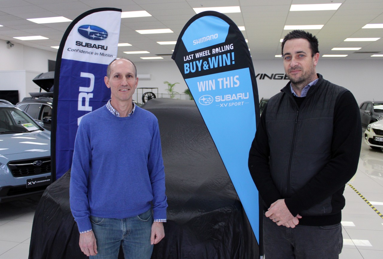 The lucky winner of the Last Wheel Rolling promotion's first prize Charles Oram (left) waits for his Subaru XV Sport to be revealed by Shimano NZ's GM Ben Ashby.