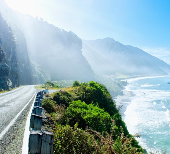 Coastal road sun flare with hills and ocean in the background